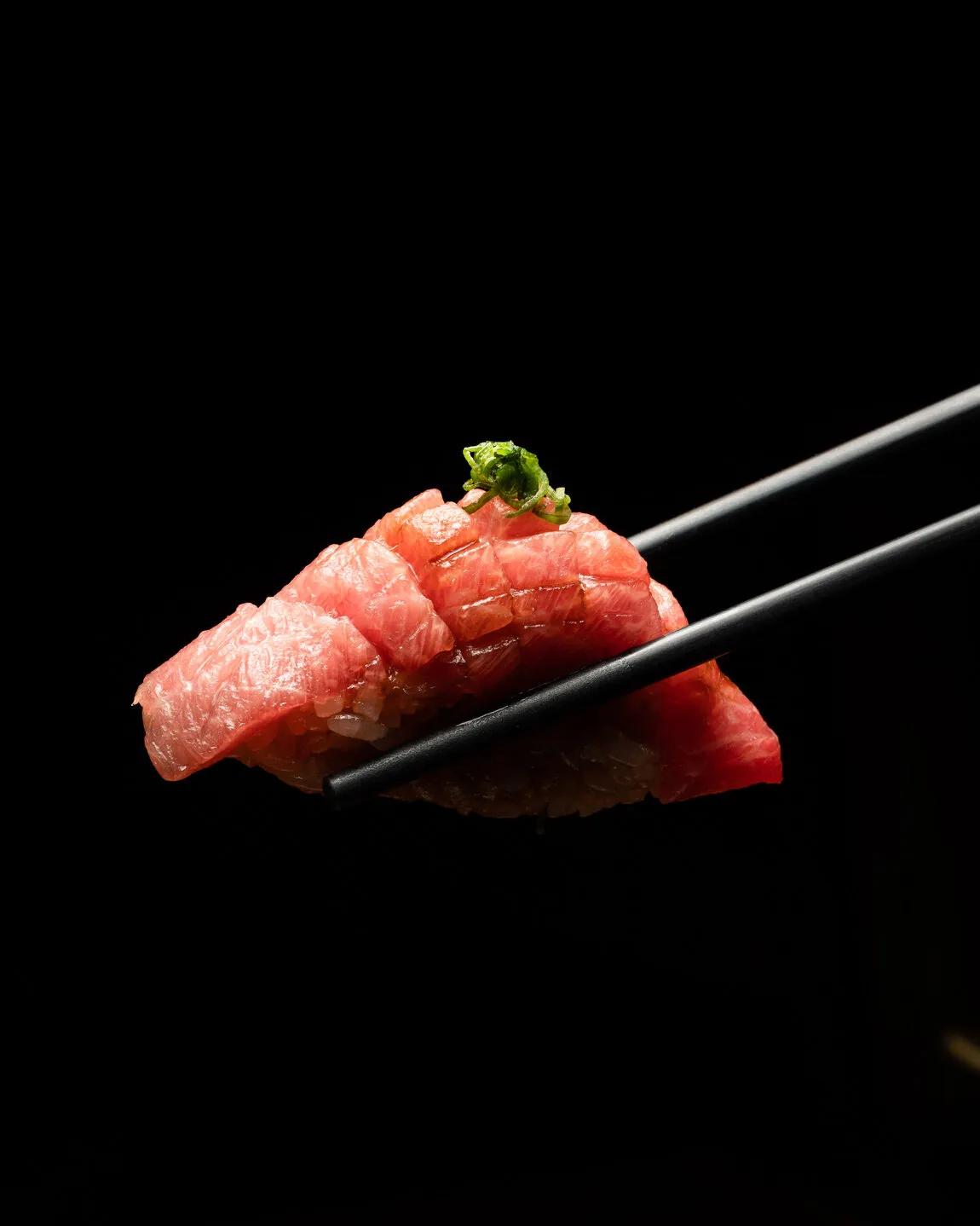 Nigiri de atún sujeto con palillos